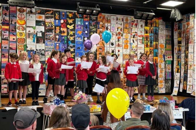 Callington Primary School Singers with the art competition work on display behind