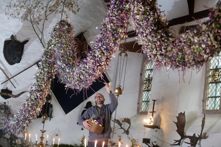 Head Gardner of 20 years Dave Bouch adding the last of the flowers to the 2024 Garland in the Great Hall at Cotehele 5. ©National Trust Images Steve Haywood