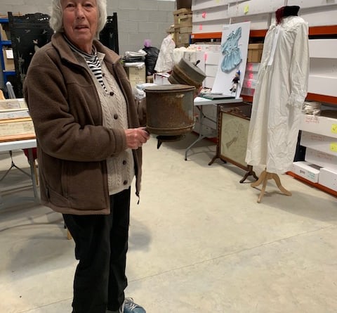 Lawrence House Museum volunteers extended a warm welcome to members of the Coad’s Green WI. Volunteer Carol Bunbury holds the ‘Mystery Object’, against a background of samplers and hand stitched clothes